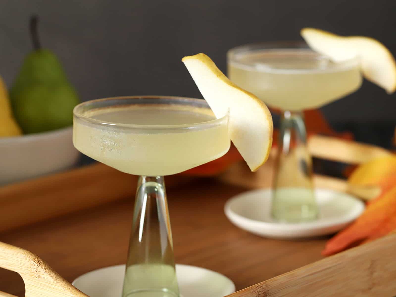 Coupe glasses filled with pear martini, garnished with slices of fresh pear.