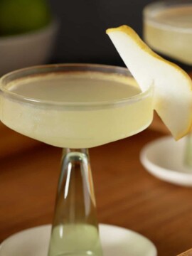 A coupe glass filled with pear martini, garnished with a slice of fresh pear.