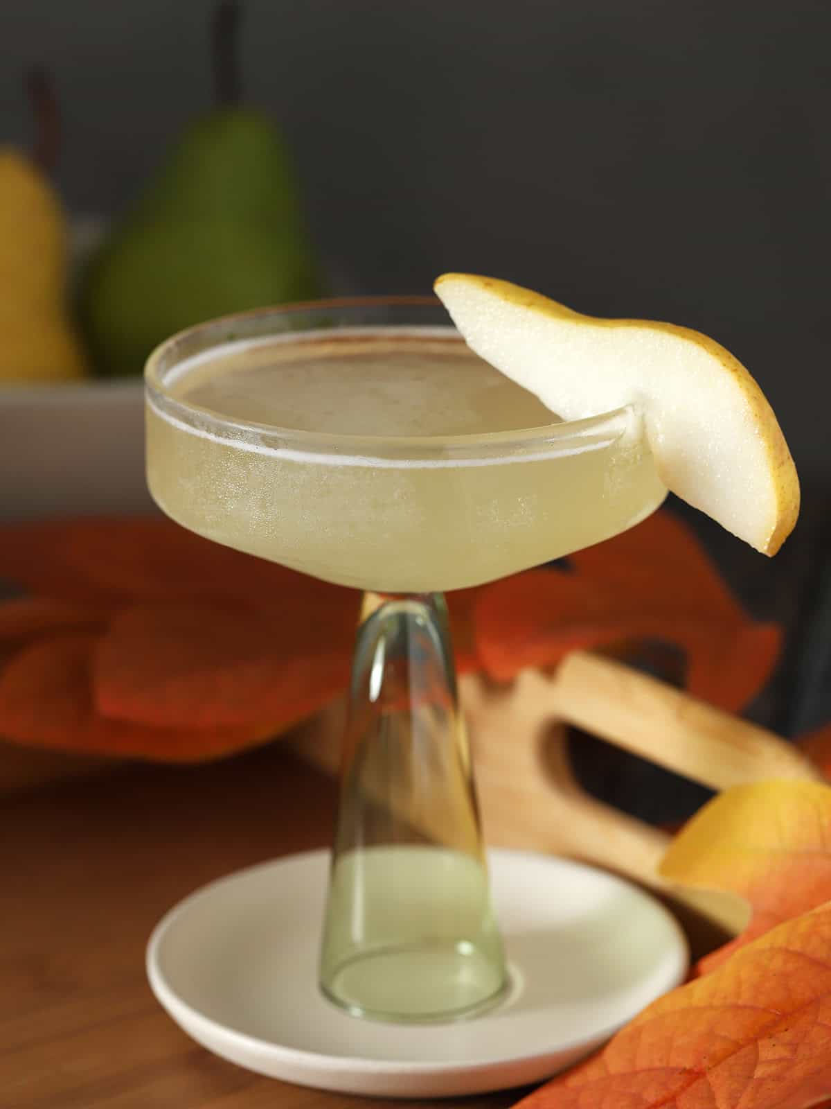A coupe glass filled with pear martini, garnished with a slice of fresh pear.