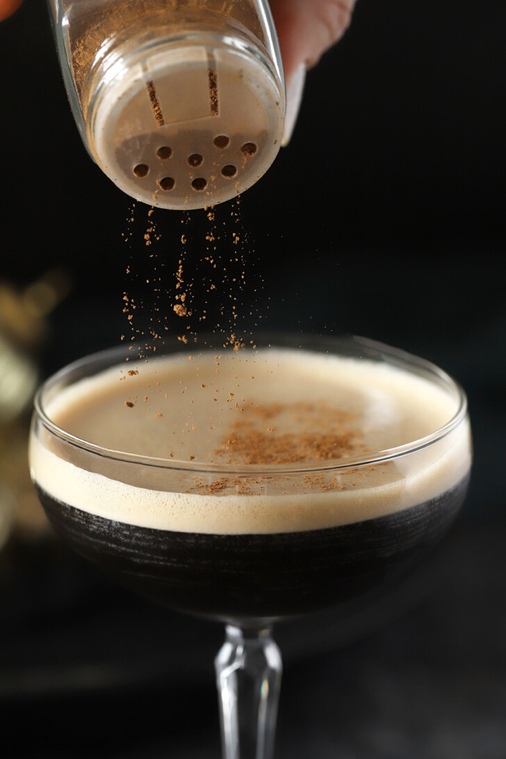 Ground cinnamon being sprinkled onto the top of a Gingerbread Espresso Martini.