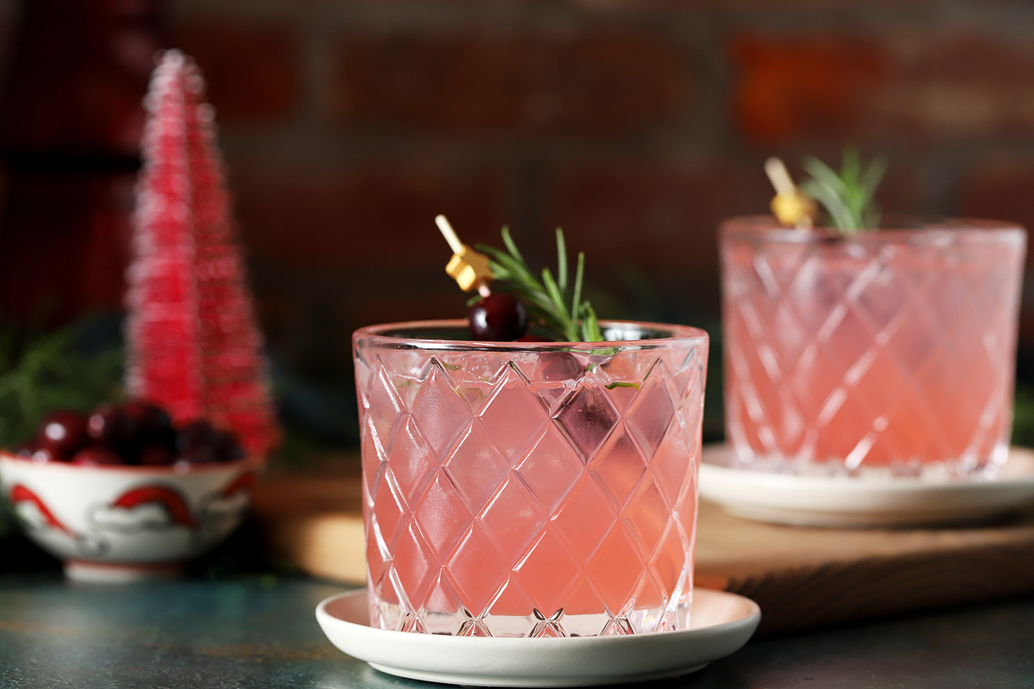 Glasses of Cranberry Mocktail garnished with a star cocktail pick with fresh cranberries and a sprig of rosemary.