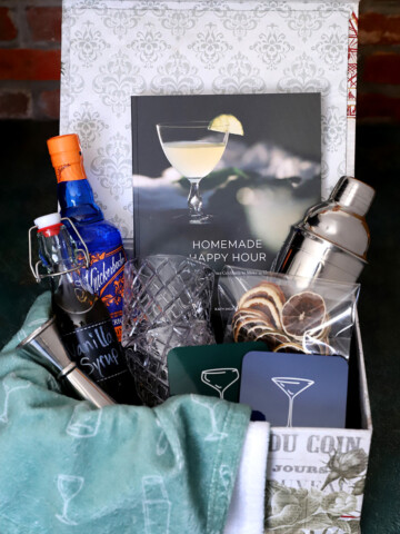 A large Christmas gift basket with cocktail related items inside.