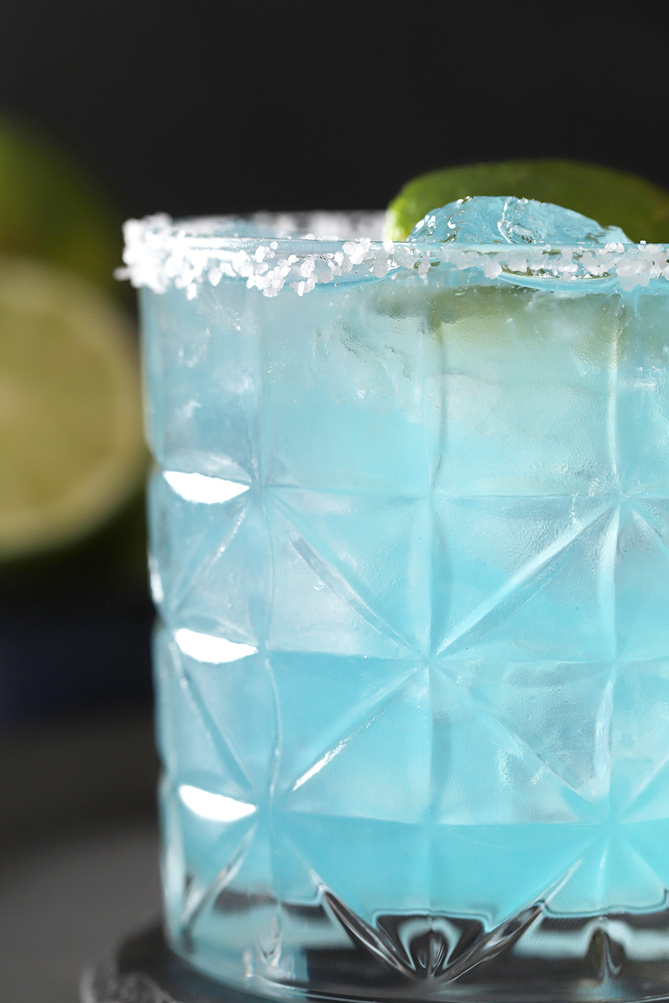 A blue margarita with a salted rim and a lime garnish. 