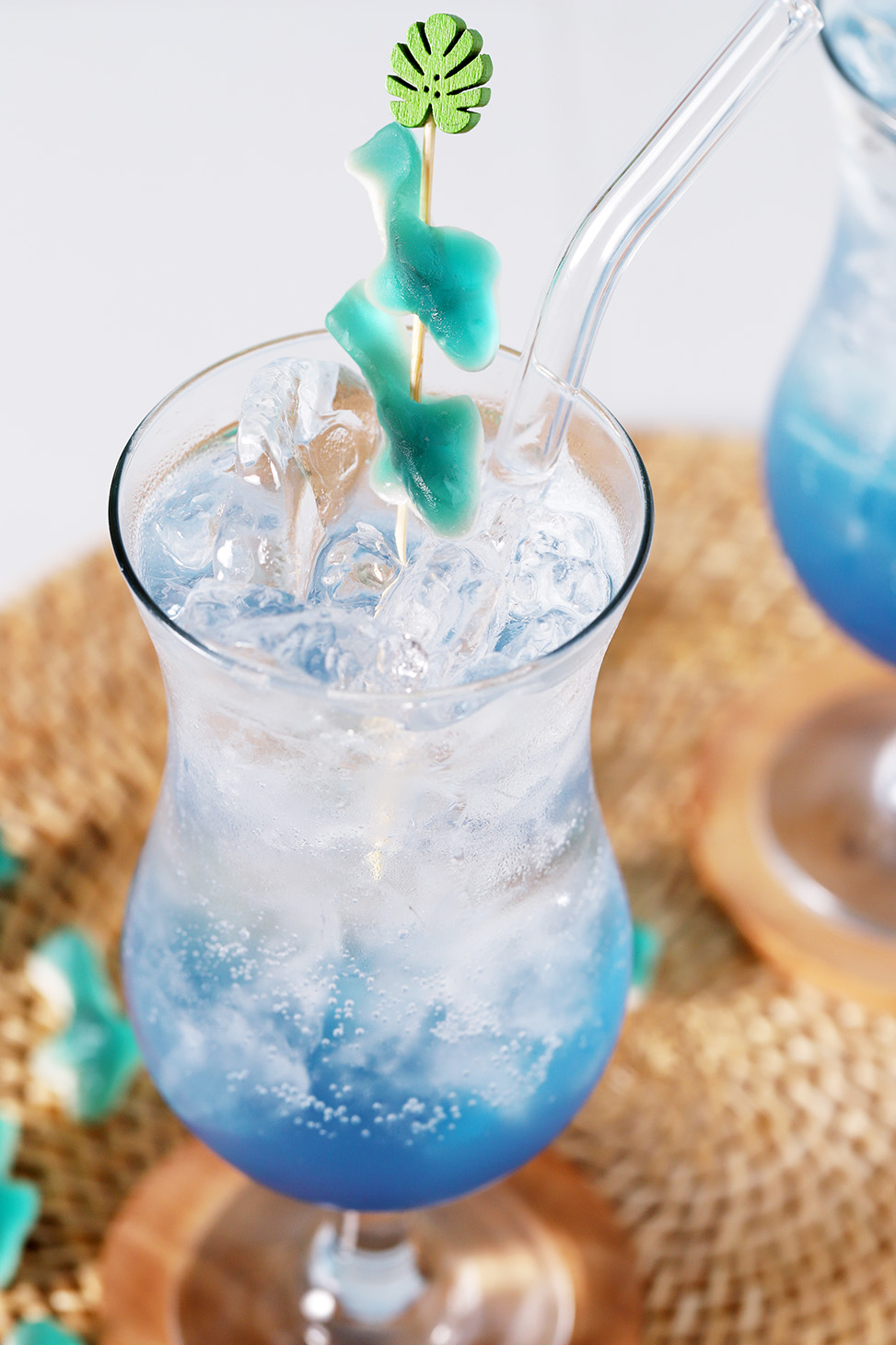 A hurricane glass filled with blue mocktail garnished with gummy sharks.