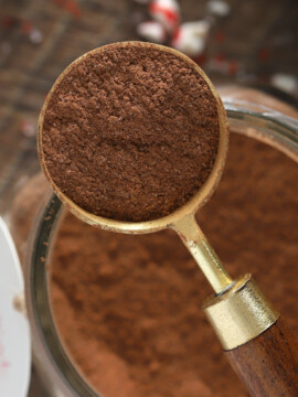 A tablespoon of peppermint hot cocoa mix setting atop a jar of mix.