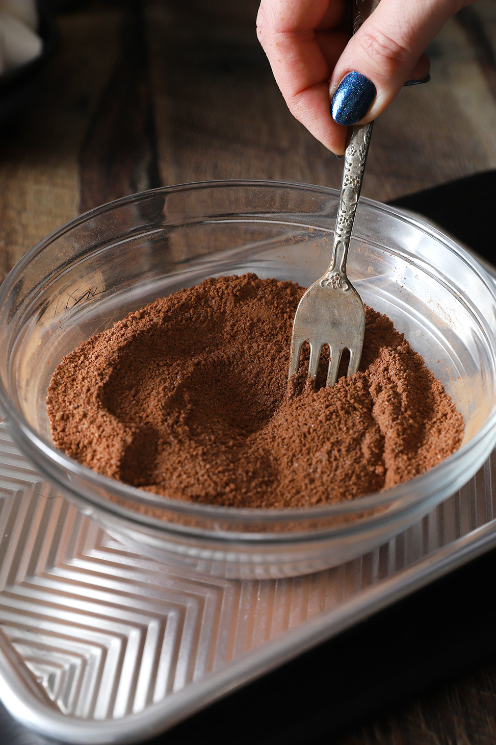 A hand using a fork to combing all ingredients together in a bowl.