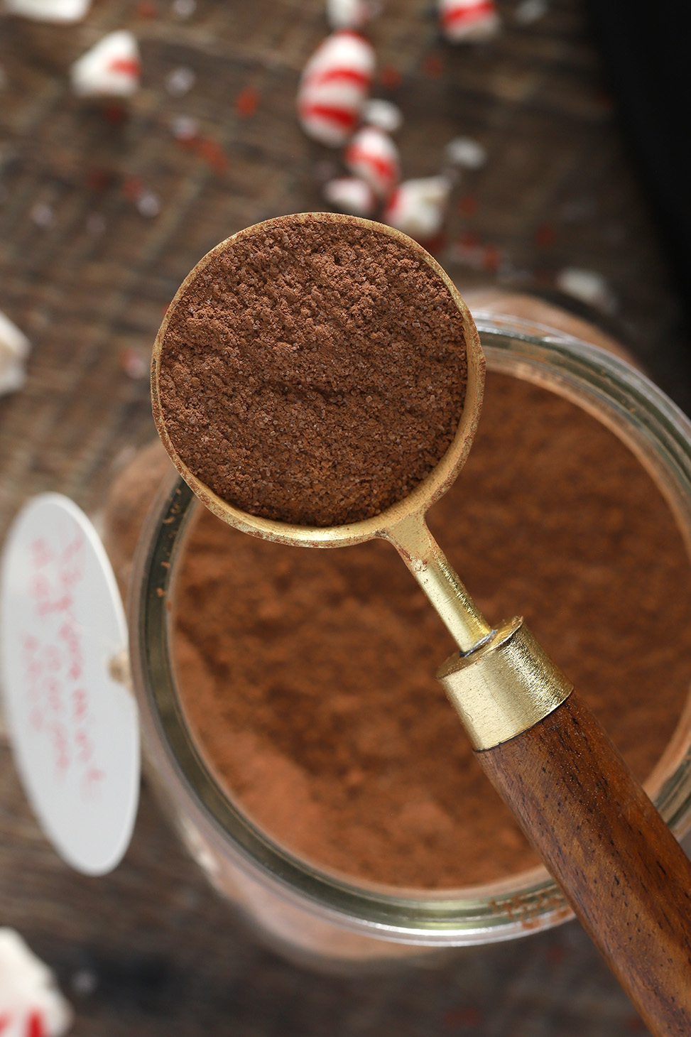 A tablespoon of peppermint hot cocoa mix setting atop a jar of mix.