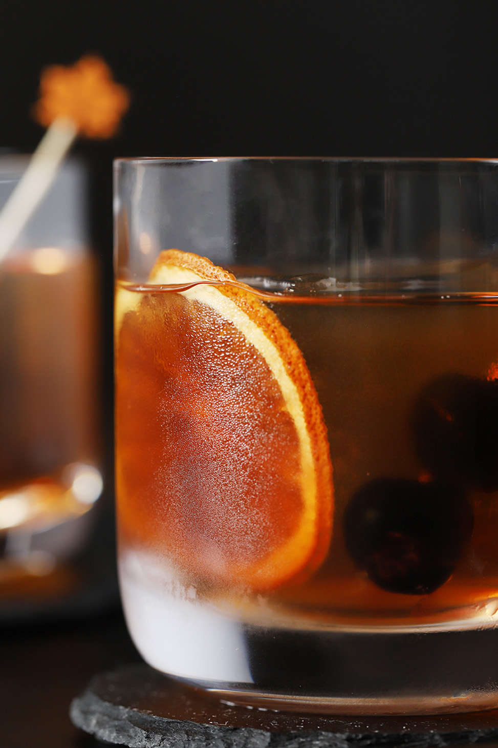A glass of Maple Old Fashioned Cocktail with a dried orange slice in it.
