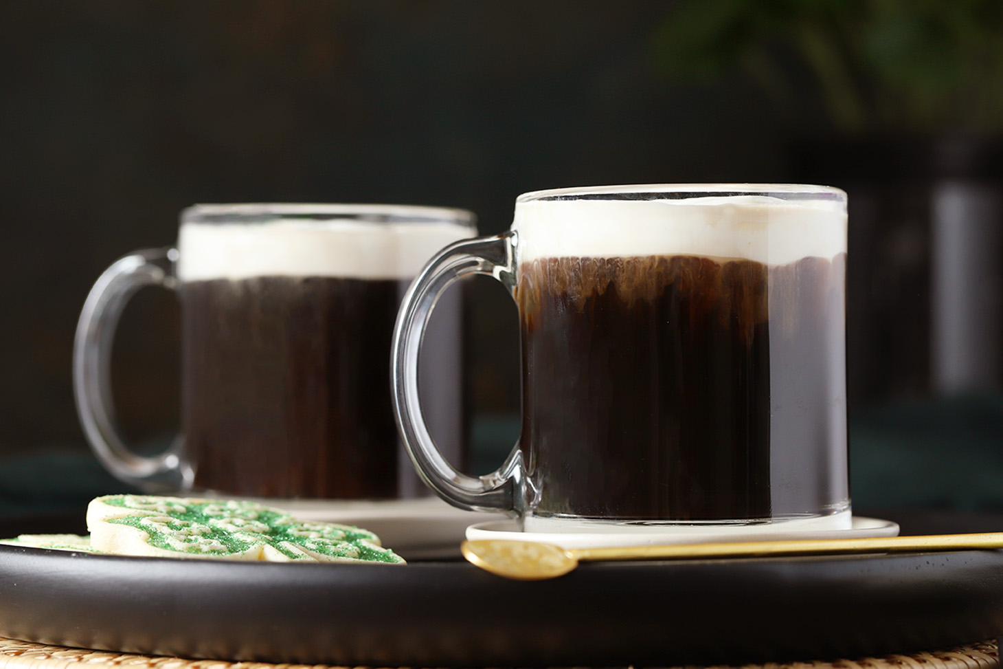 Two glass mugs of Irish coffee topped with whipped cream.