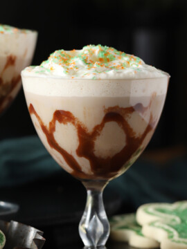Two glasses of Irish cream cocktail in glasses swirled with chocolate sauce, garnished with swirls of chocolate sauce.