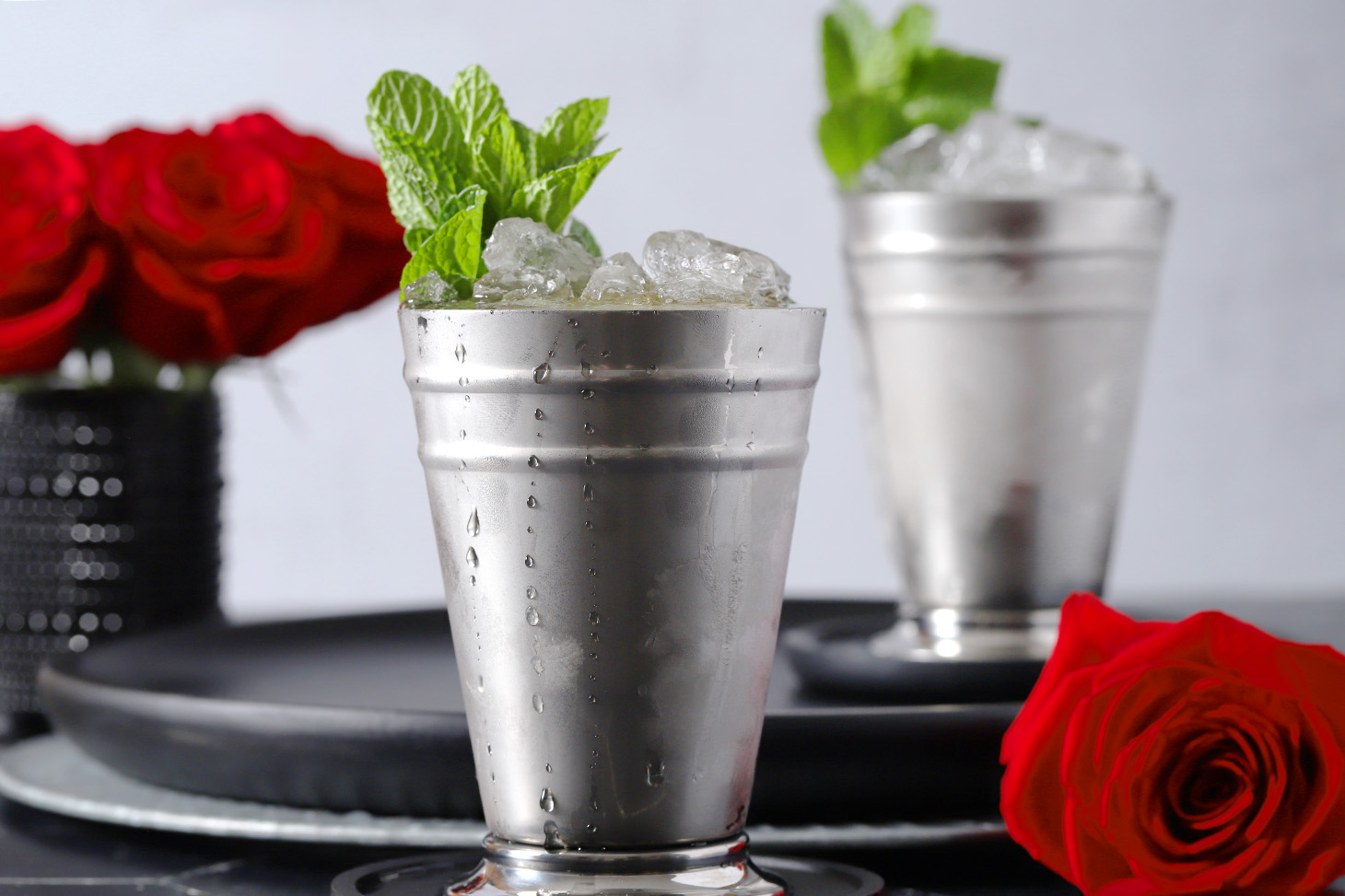 A pair of silver julep cups filled with ice and mint julep cocktails, garnished with sprigs of mint.