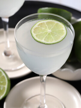 A glass of gin gimlet with a lime wheel floating on top of it.