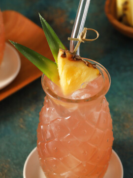A glass of Malibu Bay Breeze garnished with a wedge of pineapple and pineapple leaves.