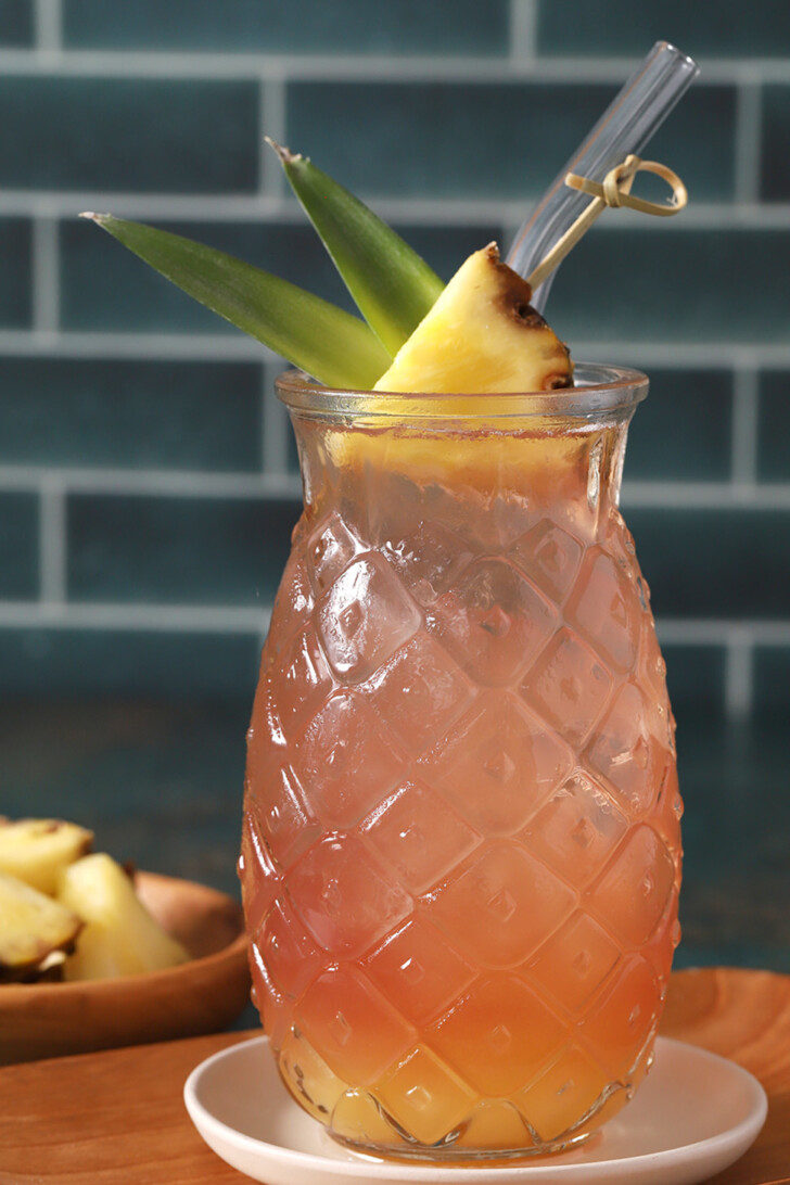 A glass of Malibu Bay Breeze garnished with a wedge of pineapple and pineapple leaves.